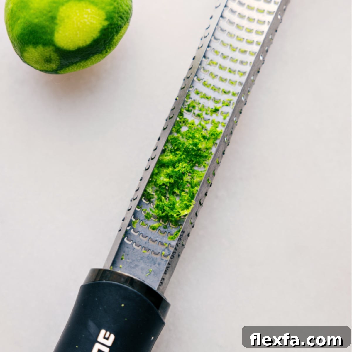 A zester tool covered in fine lime peel shavings, highlighting the fresh, green zest just removed from the fruit, ready for use in this recipe, emphasizing the importance of fresh ingredients.