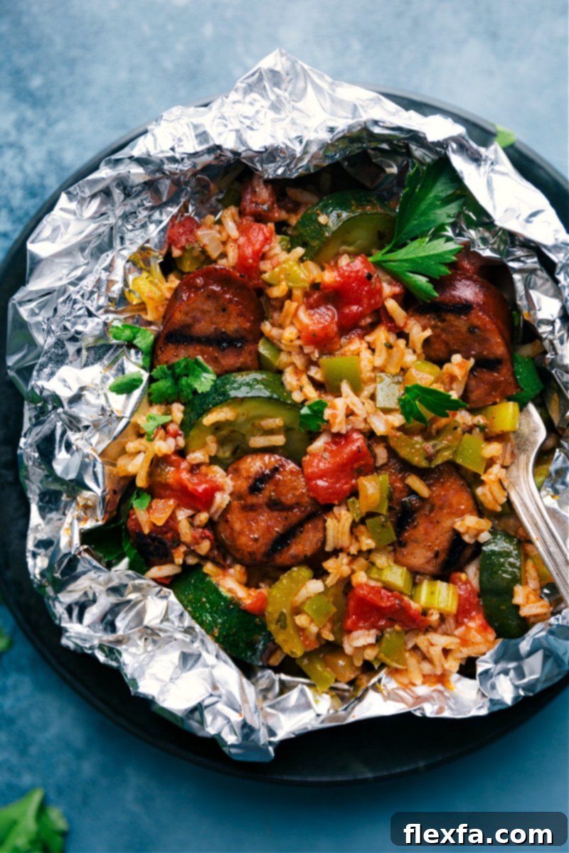 Overhead view of multiple cooked Tin Foil Jambalaya Packets, steaming slightly after being opened, showcasing the delicious contents ready to be served