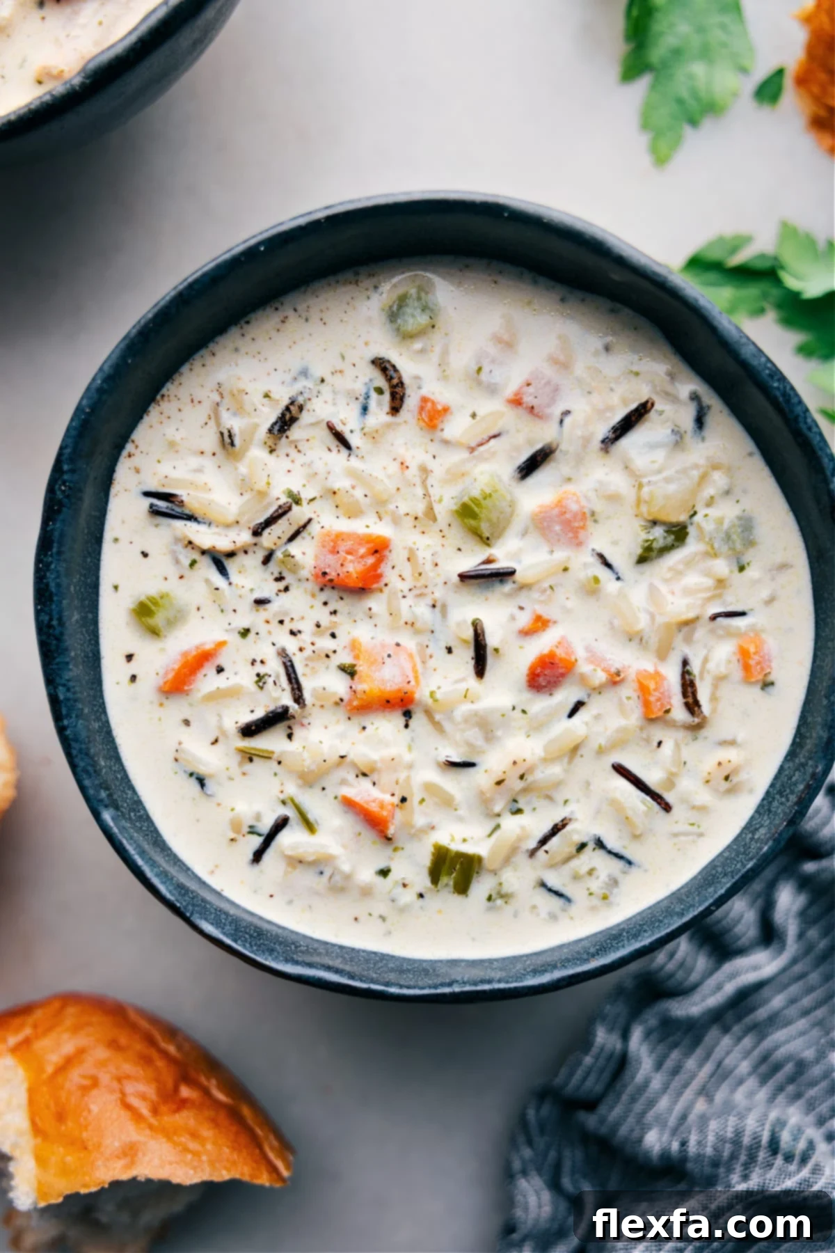 A steaming bowl of creamy chicken and wild rice soup, garnished and ready to be enjoyed.