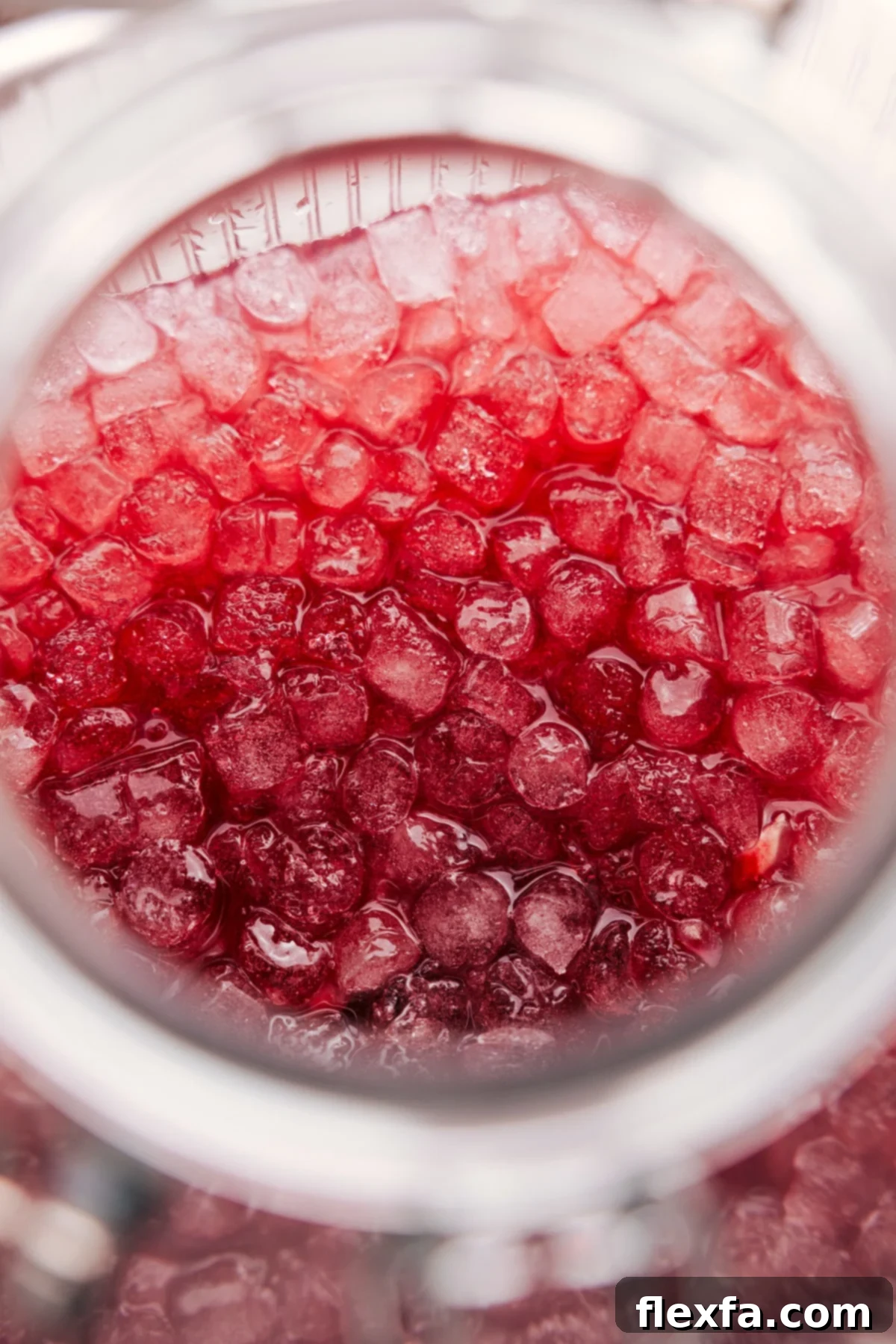 A beautifully presented glass of Christmas Punch, served over crushed ice and garnished with fresh lime and pomegranate arils, sparkling under festive lights, inviting a refreshing sip.