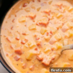 A bowl of Cheesy Potato Soup garnished with fresh herbs and bacon bits.