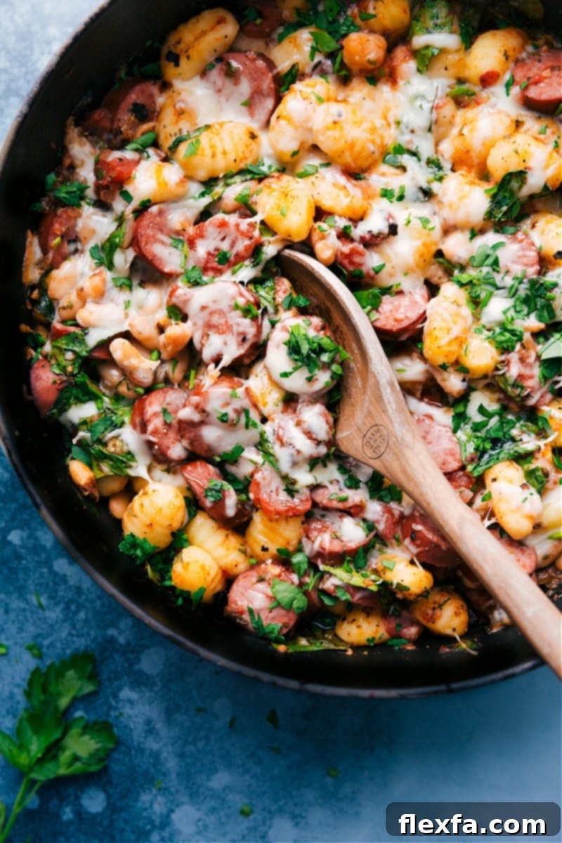 A large cast-iron skillet filled with cooked White Bean Gnocchi, golden and bubbling, straight from the oven, garnished with fresh parsley.