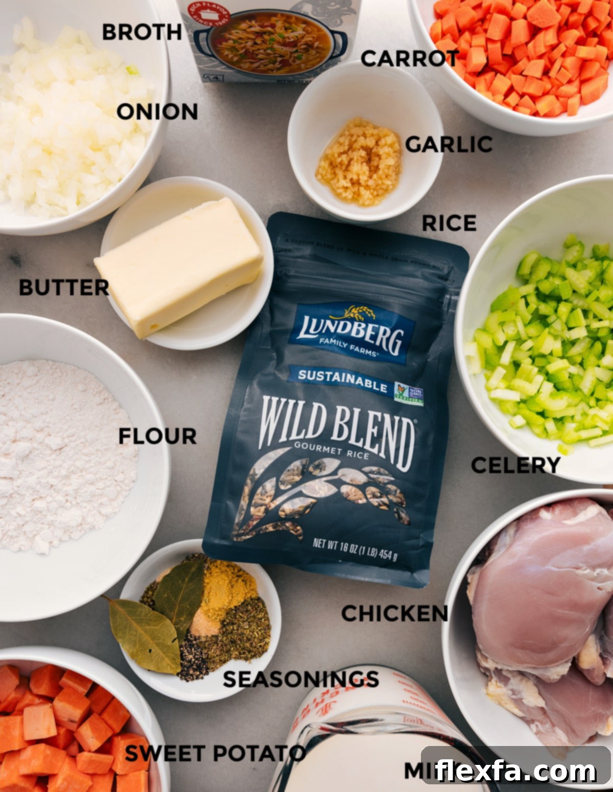 A vibrant selection of fresh ingredients for Crockpot Chicken Wild Rice Soup, meticulously prepped and laid out: diced chicken thighs, an uncooked wild rice blend, finely chopped onions, carrots, celery, minced garlic, cubed sweet potatoes, chicken stock, and a variety of dried herbs and spices.
