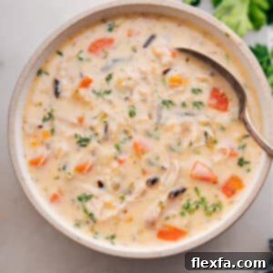 A close-up of a rustic bowl filled with creamy Crockpot Chicken Wild Rice Soup, highlighting the rich texture and ingredients.