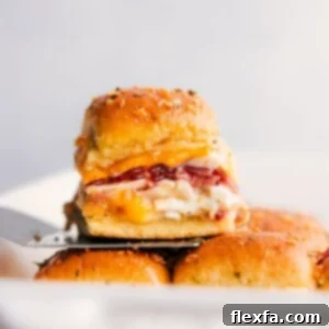 Stack of golden-brown Chicken Bacon Ranch Sliders, with one ready to be served on a spatula.