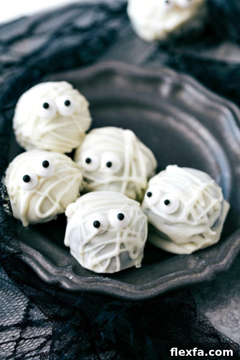Spooky white Mummy Oreo Truffles with dark edible eyes, perfect for a Halloween treat table.