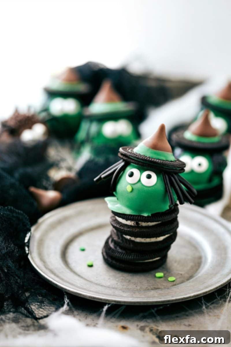A vibrant green Witch Oreo Truffle with a pointy hat, edible eyes, and licorice hair, displayed against a Halloween backdrop.