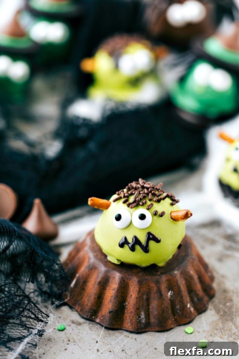 A green Frankenstein Oreo Truffle with pretzel bolts, edible eyes, and a drawn-on mouth, ideal for Halloween festivities.