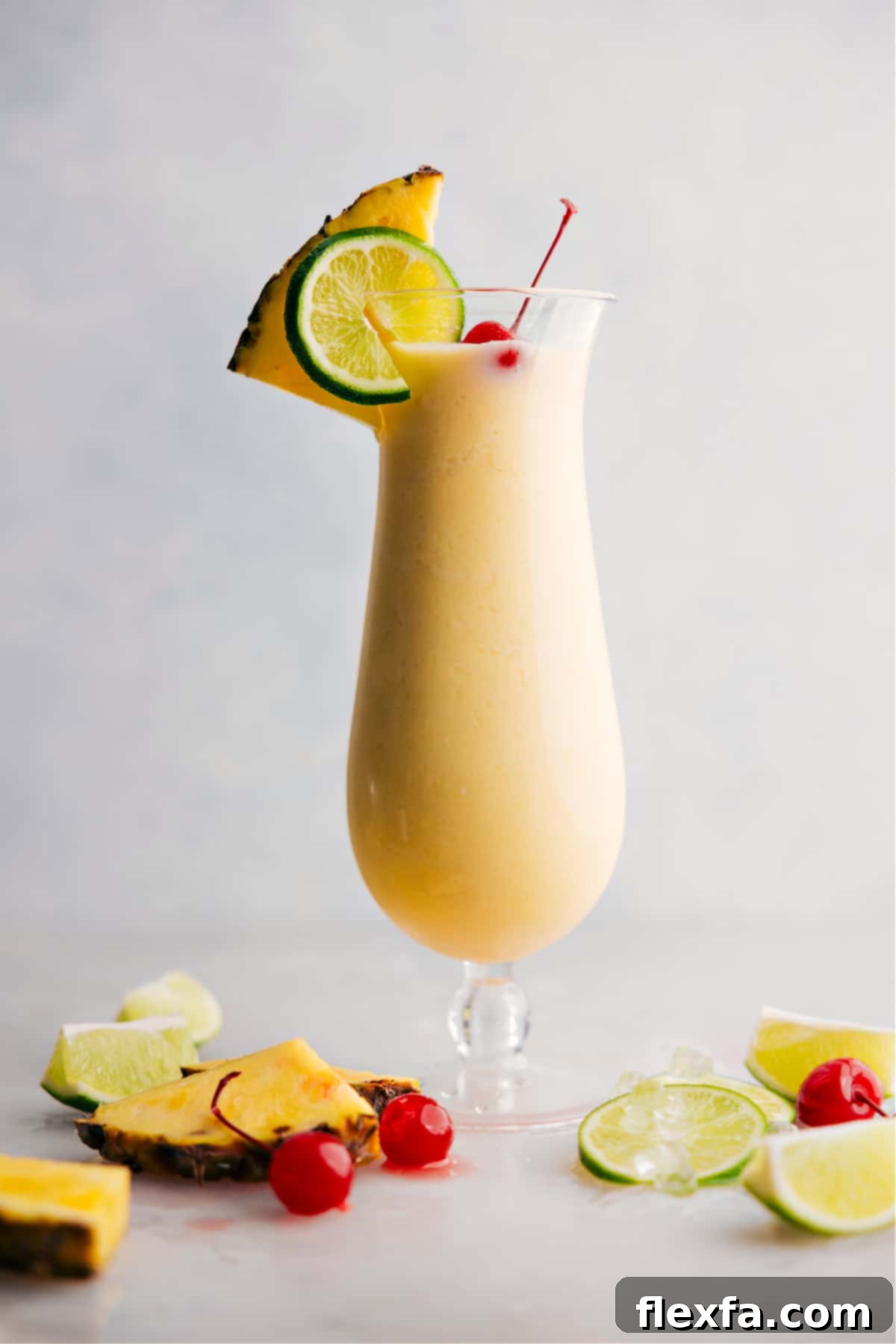 Perfect Pina Colada Drink A perfectly blended Pina Colada in a hurricane glass, garnished with a pineapple wedge and cherry, ready to be enjoyed.