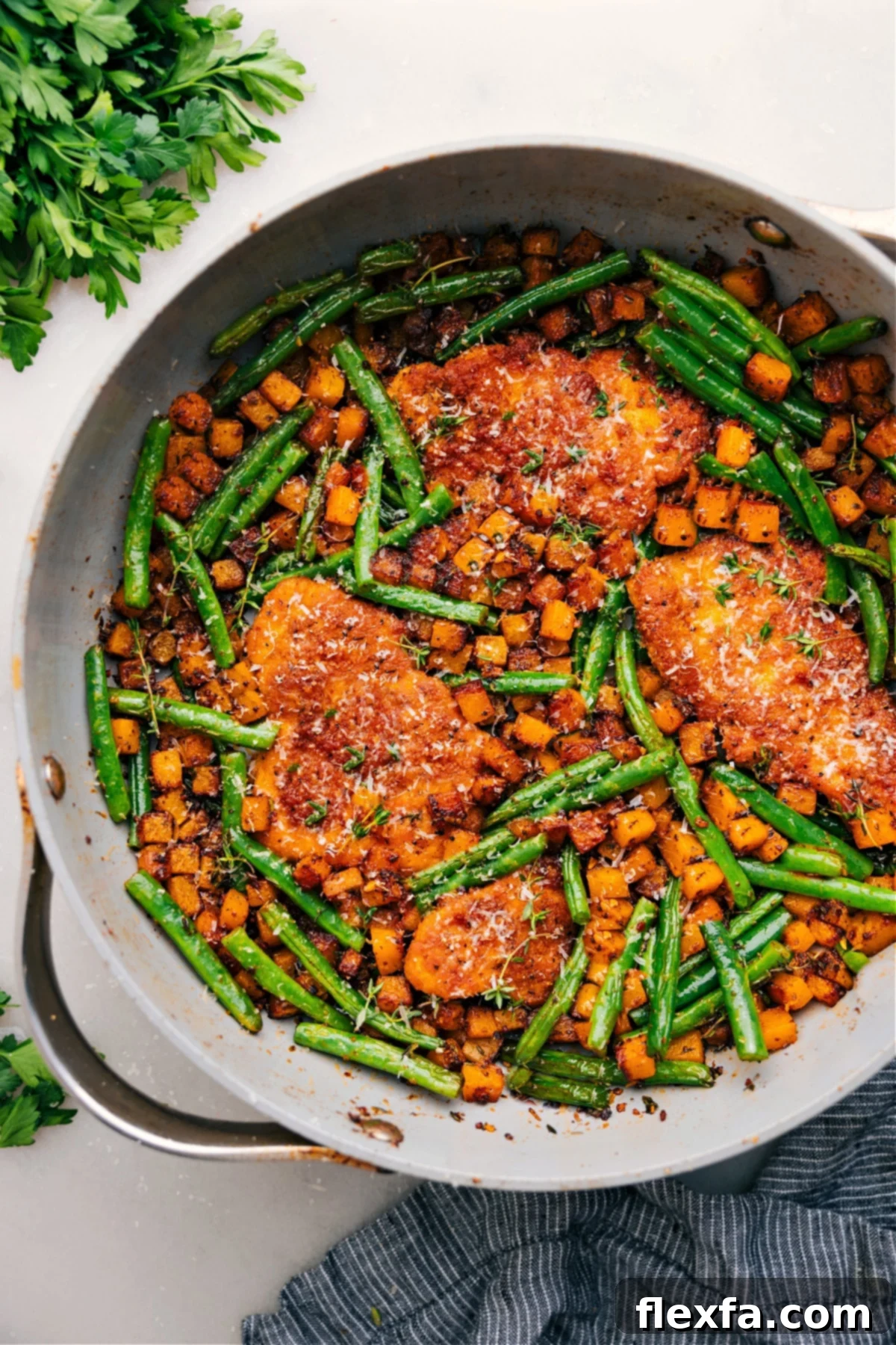 One skillet Chicken and Butternut Squash with fresh parmesan on top, garnished with herbs.
