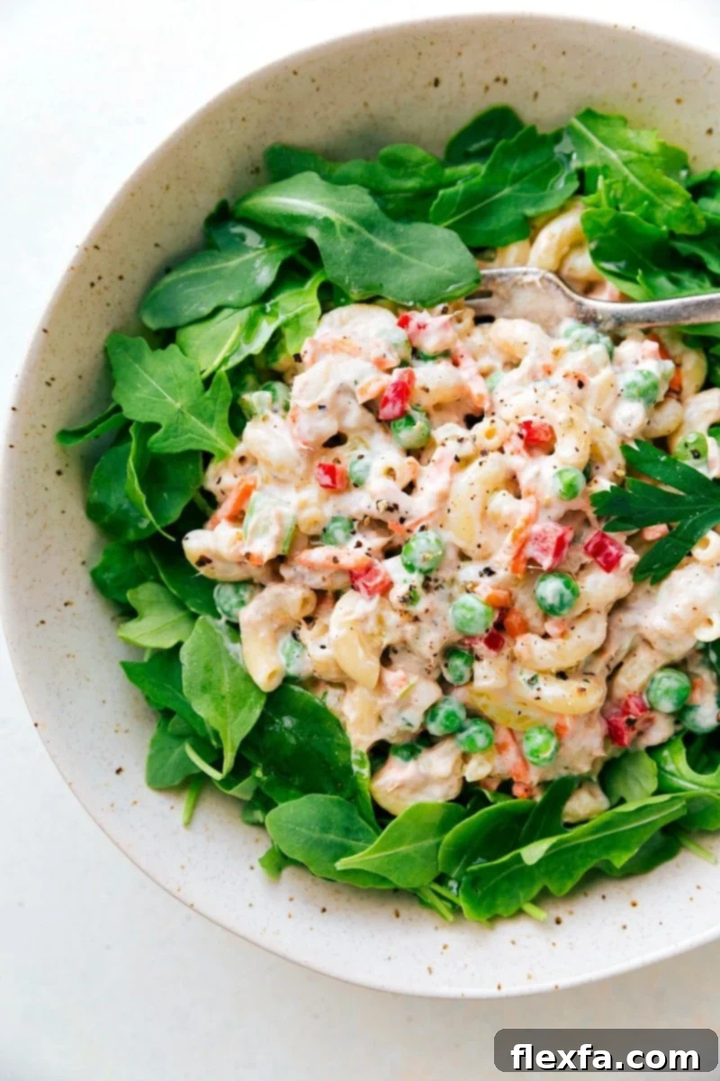 This is our absolute favorite creamy Tuna Macaroni Salad! Rich and creamy Tuna Macaroni Salad in a serving bowl, garnished with fresh herbs, ready to be enjoyed.