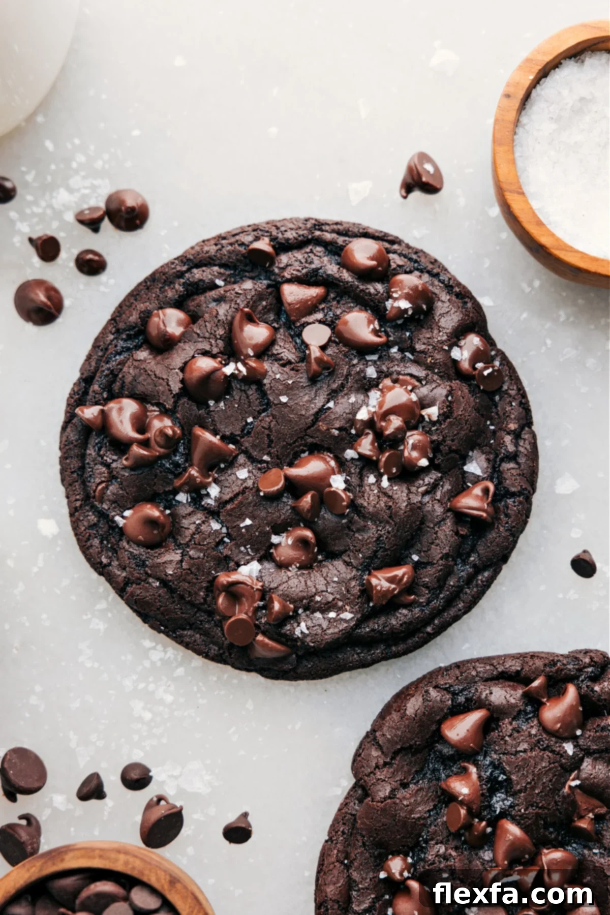 A beautifully presented Single Serve Double Chocolate Cookie, viewed from above, adorned with flaky sea salt. The image highlights its rich, dark color and visible chocolate chips, promising a decadent experience.
