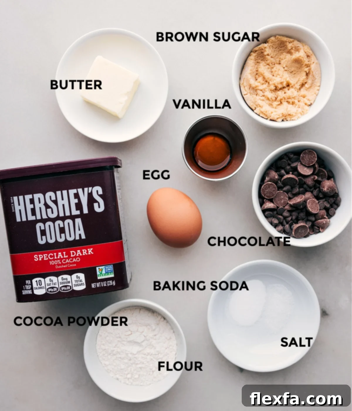 All the essential ingredients for making Single Serve Double Chocolate Cookies, meticulously prepped and laid out for easy assembly, including unsalted butter, light brown sugar, egg yolk, vanilla extract, all-purpose flour, Dutch process cocoa powder, baking soda, salt, and chocolate chips.