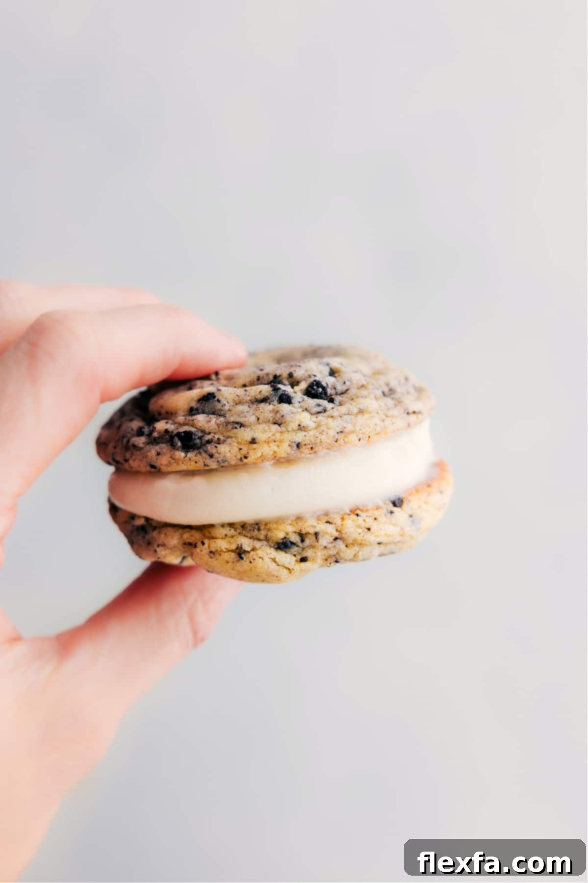 A single Oreo Whoopie Pie held up, showcasing its perfectly soft chocolate cookie layers and generous swirl of creamy frosting in the center, highlighting its deliciousness.