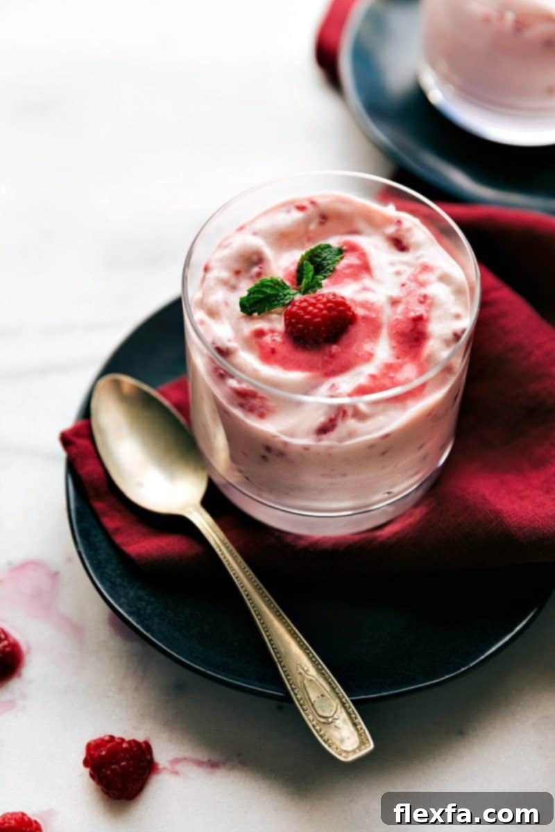 A single serving of Raspberry Fluff in a glass cup with a spoon on the side, ready to eat
