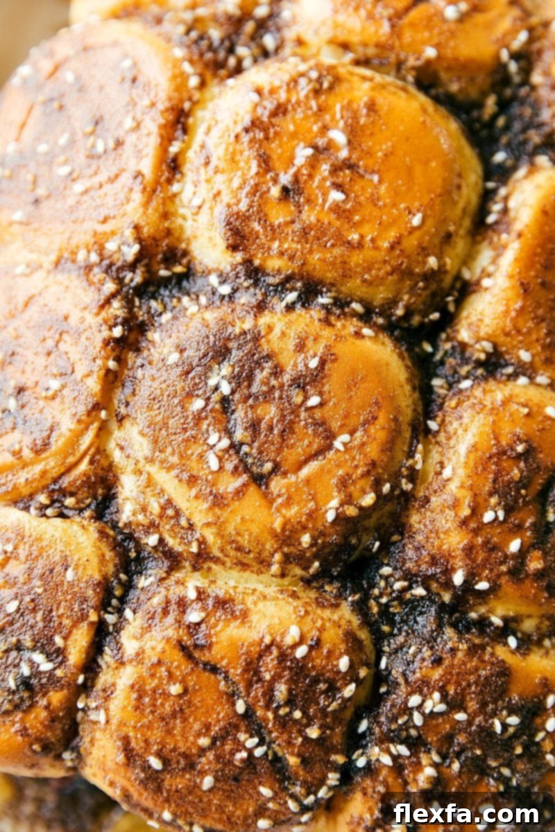 French Dip sliders arranged neatly in a baking pan, fresh out of the oven, with golden-brown tops and melted cheese visible.