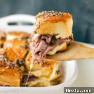 French Dip sandwiches fresh out of the oven with a spatula pulling one out.