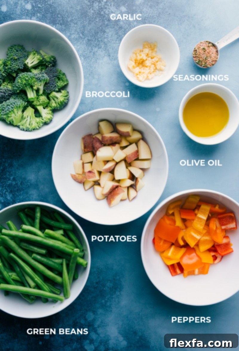 An array of fresh, colorful vegetables including broccoli, red potatoes, bell peppers, and green beans, prepped and ready for roasting with garlic and olive oil.