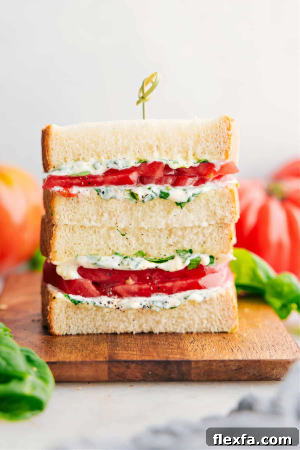 Tomato Sandwich stacked on top of each other showing the delicious inside with vibrant red tomatoes and green basil mayo.