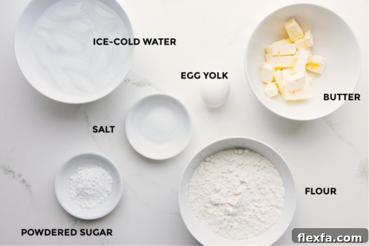All the essential ingredients for a perfect pie crust: flour, unsalted butter, egg yolk, salt, powdered sugar, and a bowl of ice cold water, meticulously prepped and ready for assembly.