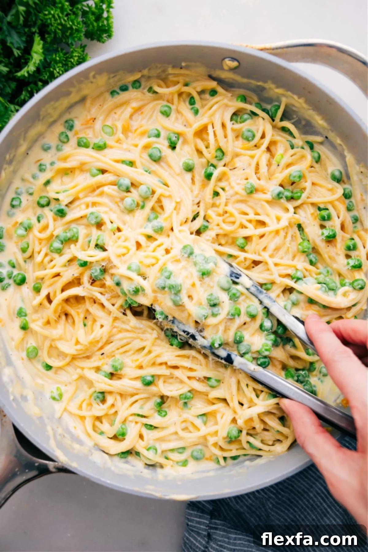 A large pot filled with creamy cheesy spaghetti, perfectly cooked and ready to be served, with a scoop lifting some of the delicious pasta.