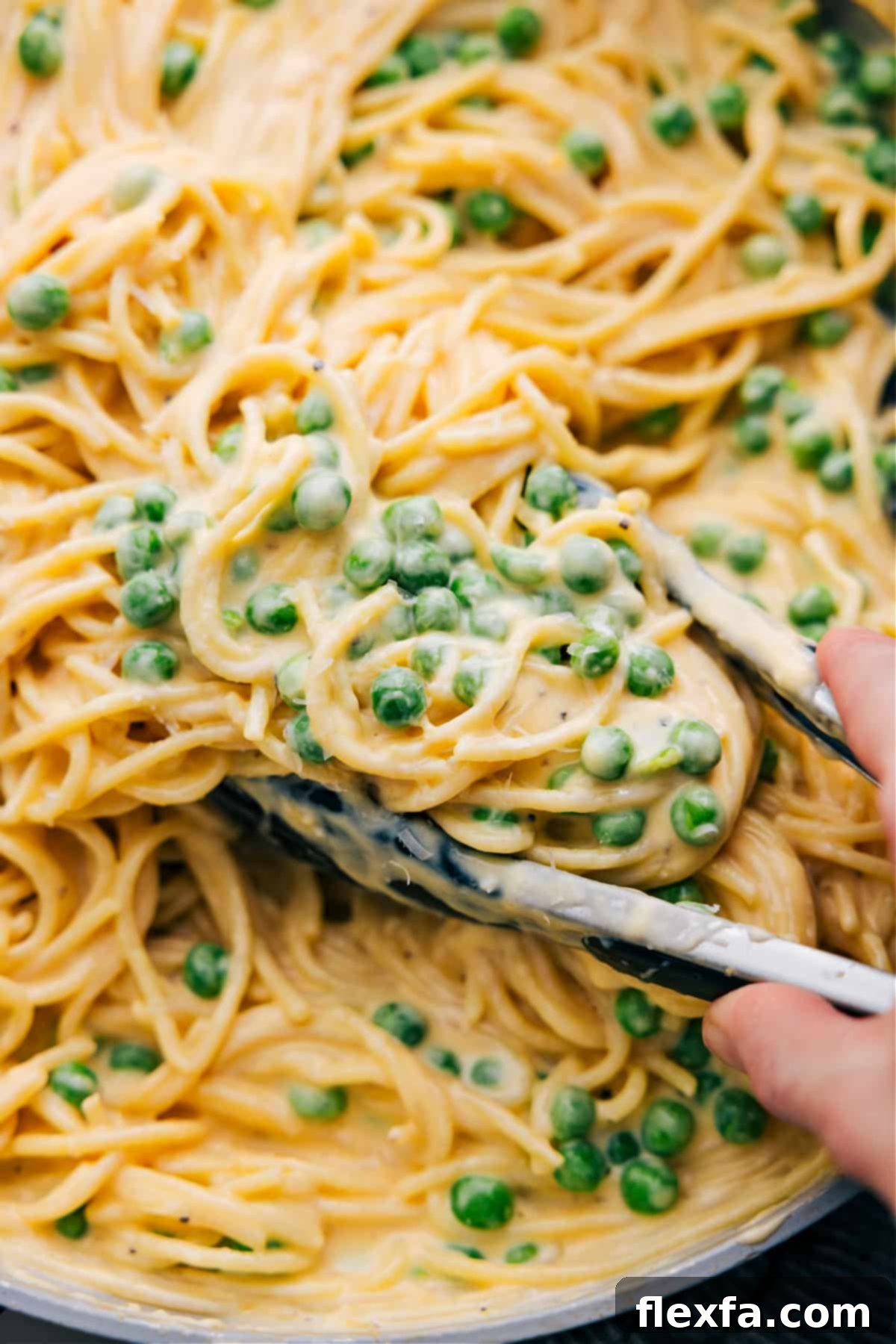A beautiful close-up of a serving of creamy cheesy spaghetti with vibrant green peas, garnished with fresh herbs, elegantly plated and ready to be enjoyed.