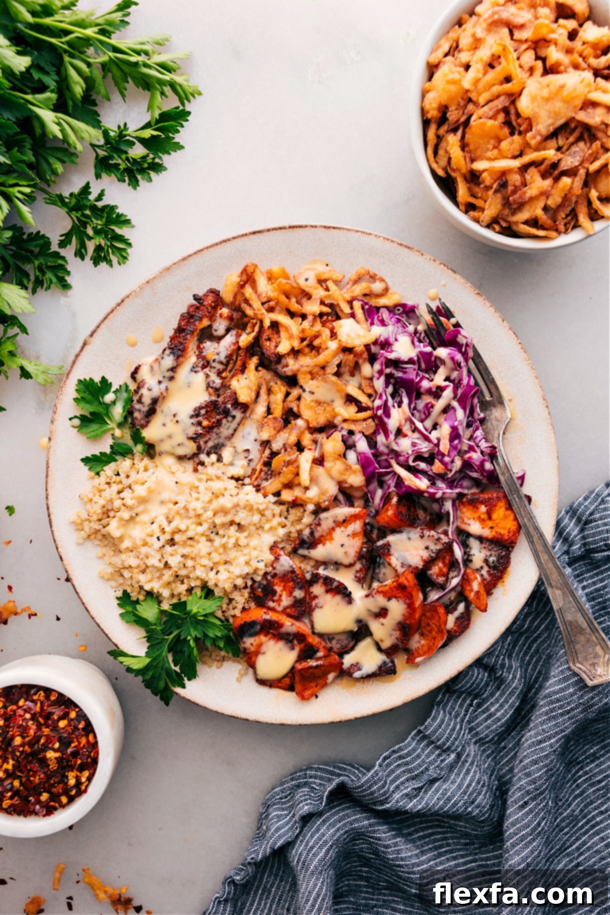 A vibrant Hot Honey Chicken Bowl topped with creamy dressing and crispy fried onions, ready to be enjoyed.