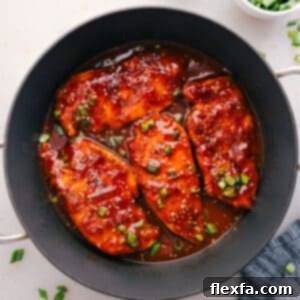 A serving of Honey Garlic Chicken with rice, garnished with green onions and sesame seeds.