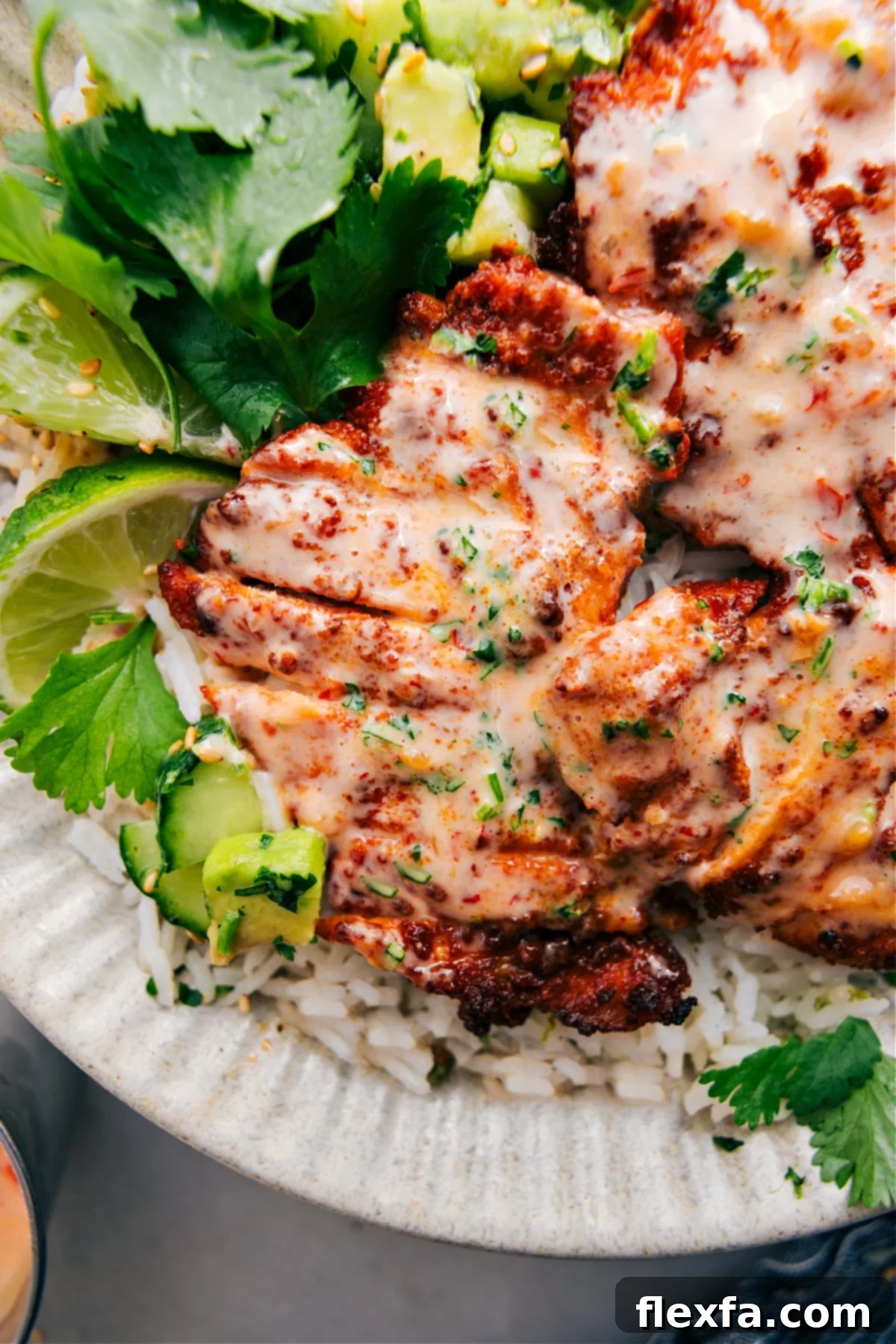 Bang Bang Chicken served on a bed of rice, topped with Bang Bang sauce and a sprinkle of lime zest.