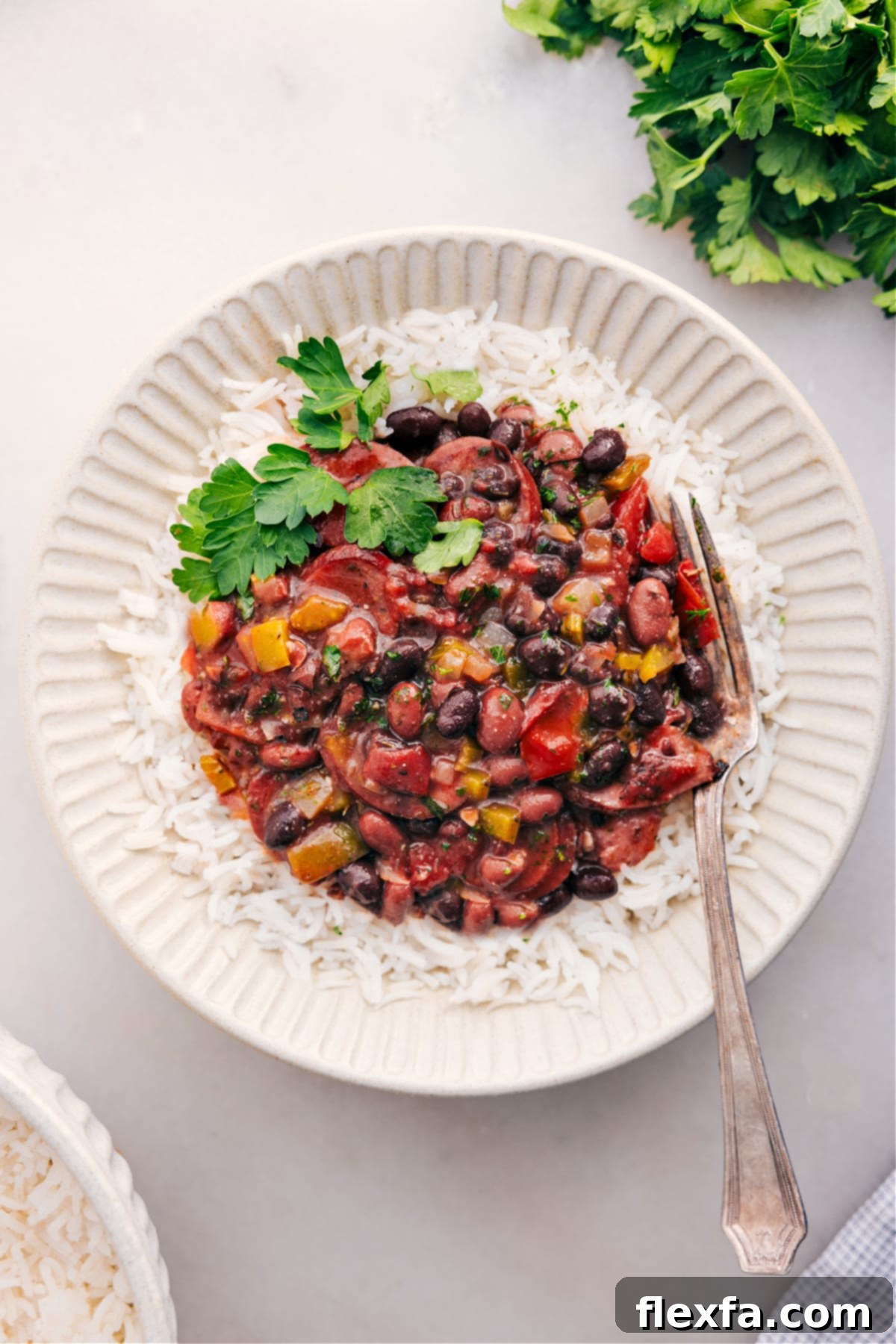 Delicious slow cooked black beans and sausage served over fluffy white rice, garnished with fresh herbs.