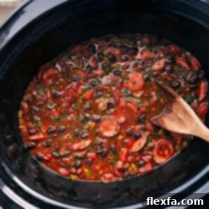 A delicious bowl of Black Beans and Sausage served over rice, garnished with fresh herbs and a lemon wedge.