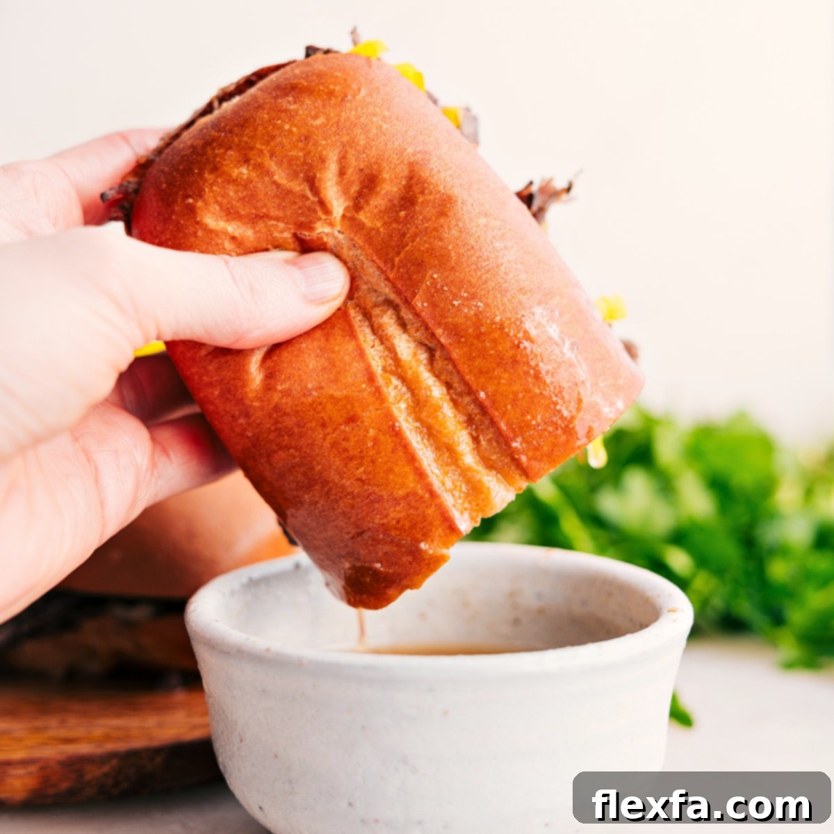 Dip Italian Beef Sandwich In Leftover Broth An Italian Beef Sandwich being dipped into a small bowl of rich, savory broth, highlighting the 'au jus' tradition.