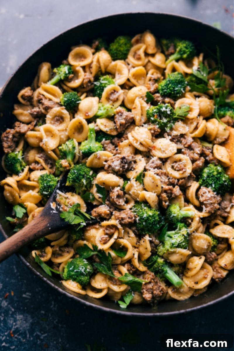 Overhead image of Orecchiette, Sausage, and Broccoli Pasta, garnished with fresh parsley and Parmesan, ready to be served in a large skillet.
