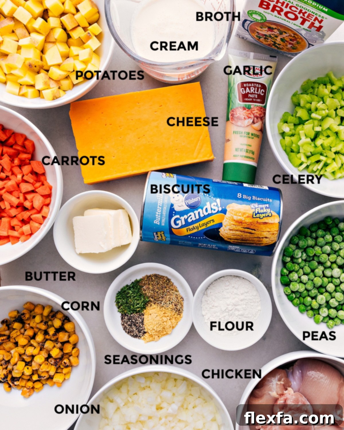 All the essential ingredients for Crockpot Chicken Pot Pie meticulously prepped and laid out, including vibrant vegetables, creamy dairy, seasoned chicken, and flaky biscuits, ready for assembly.