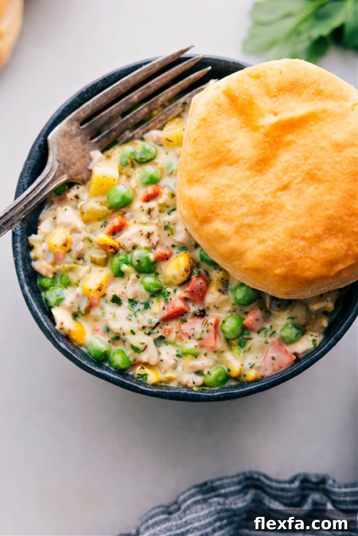 A hearty serving of Crockpot Chicken Pot Pie, featuring a golden, creamy filling topped with a generous sprinkle of melted cheese, promising a comforting weeknight dinner.