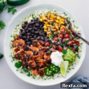 Close-up of a vibrant Chicken Burrito Bowl with seasoned chicken, rice, beans, corn, and avocado.
