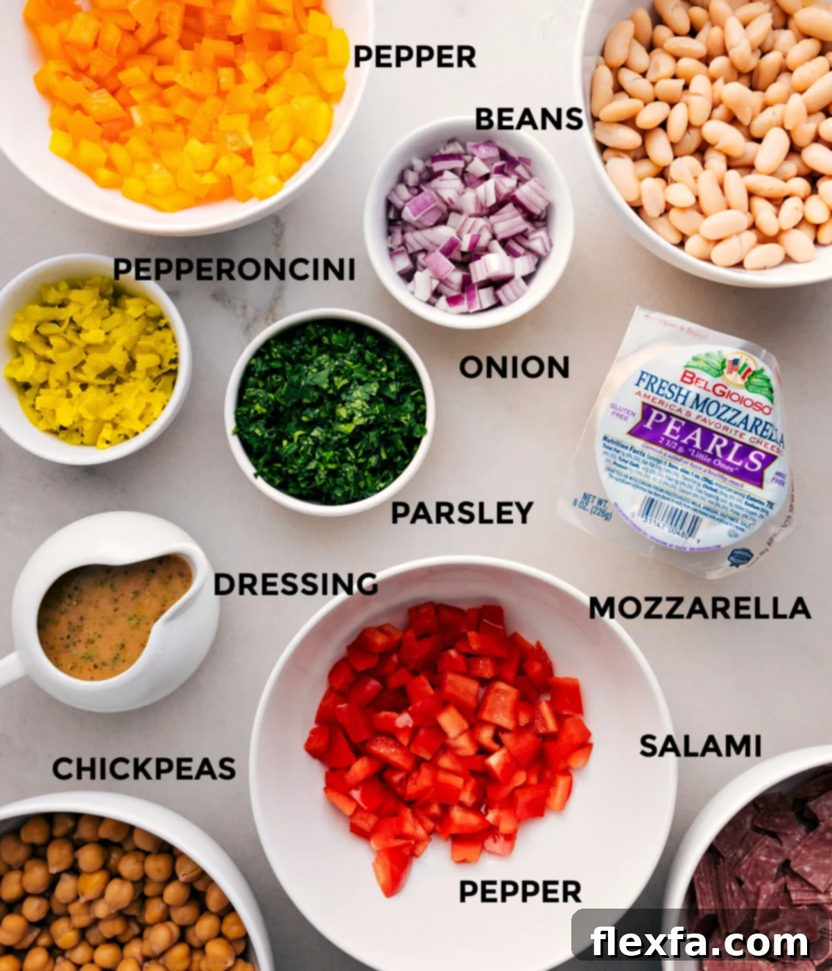 Ingredients In Dense Bean Salad Recipe All the vibrant ingredients for the Dense Bean Salad laid out: canned chickpeas, cannellini beans, diced red onion, fresh parsley, small mozzarella pearls, sliced pepper salami, sweet bell peppers, and pepperoncini peppers.