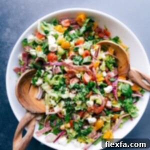 Colorful and vibrant Italian chopped salad with wooden serving spoons in the bowl.
