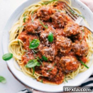 Plated cheese stuffed meatballs on spaghetti with fresh basil garnish