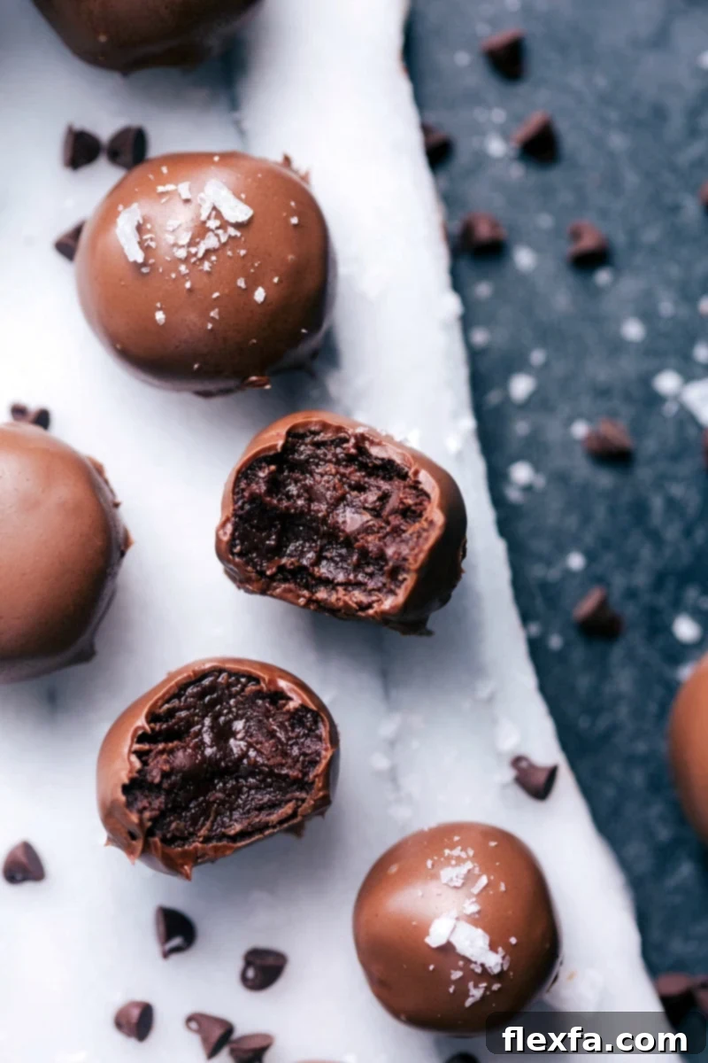 Irresistibly Fudgy No-Bake Brownie Bites: A Quick & Easy Indulgence Delicious No-Bake Brownie Bites coated in chocolate with sea salt flakes on a light background.