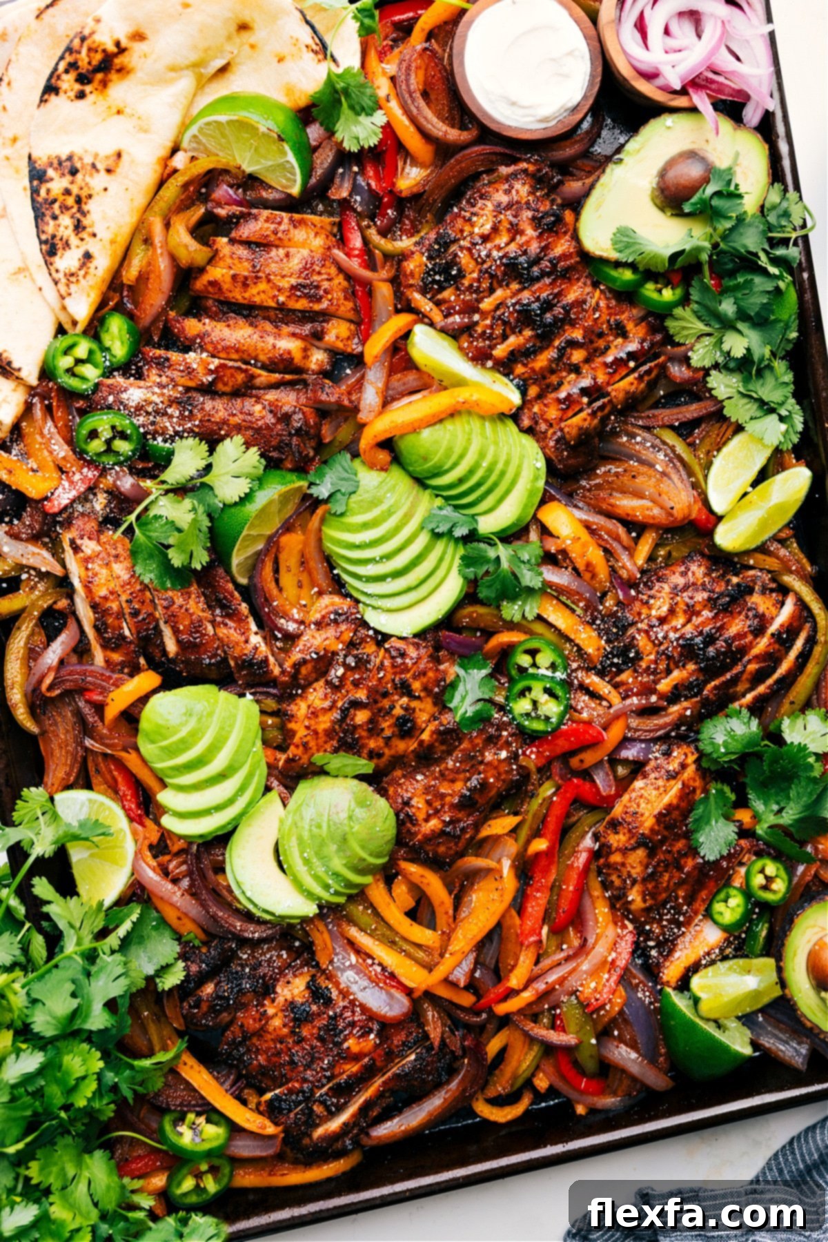Make An Entire Chicken Fajita Dinner On One Sheet Pan Sheet Pan Chicken Fajitas on the pan topped with fresh avocado, jalapeños, and cilantro.
