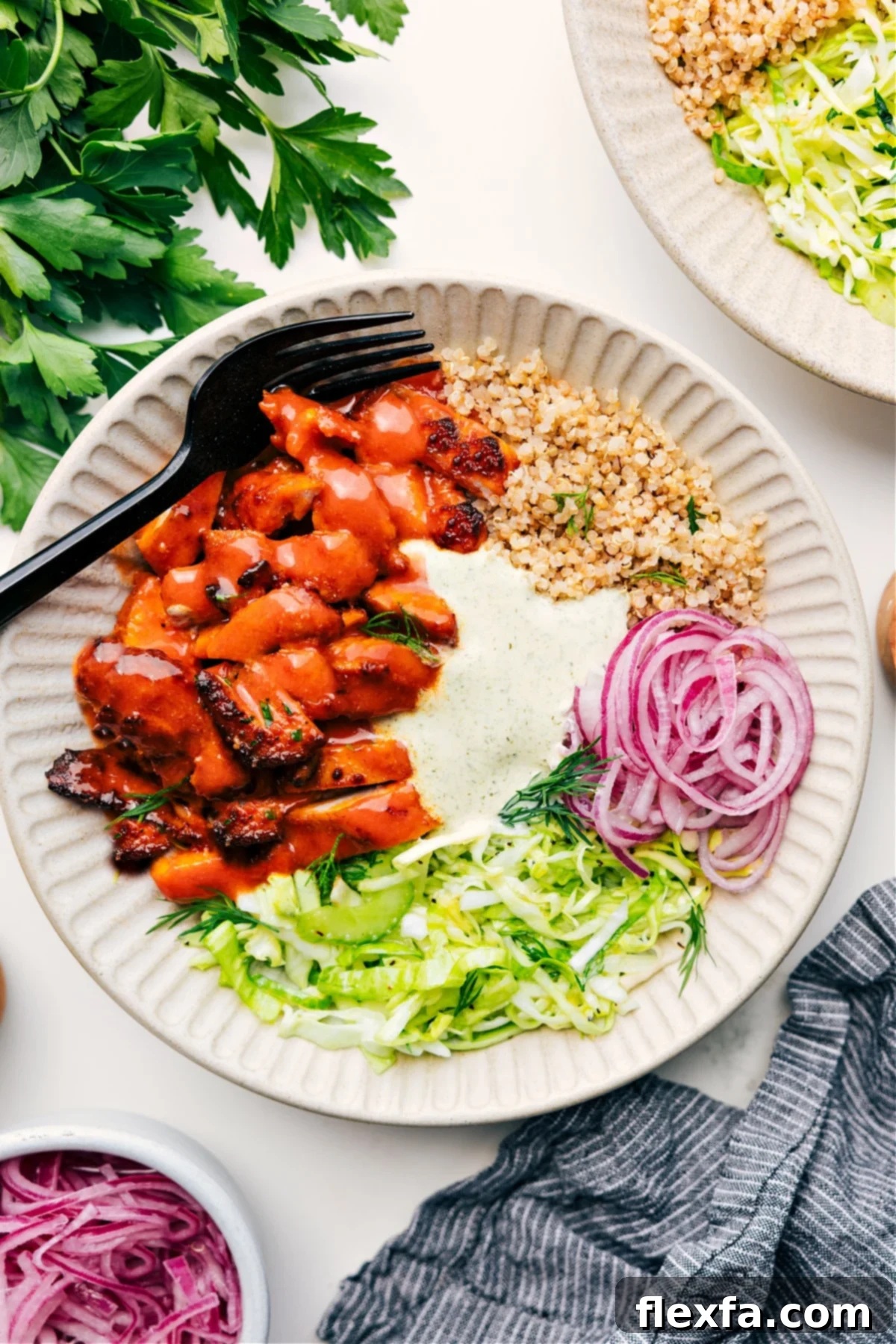 Buffalo Chicken Bowl served over quinoa, topped with slaw, pickled red onions, and a creamy sauce.