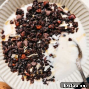 Close-up of freshly baked, chunky chocolate granola with visible oats, nuts, and melted chocolate, inviting you to take a bite.