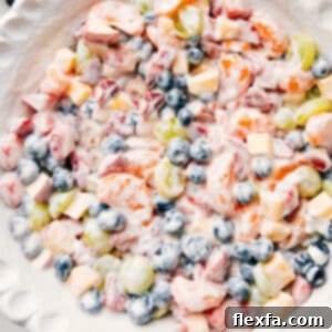 A vibrant fruit salad with creamy yogurt dressing, presented beautifully in a white bowl, ready to be served.