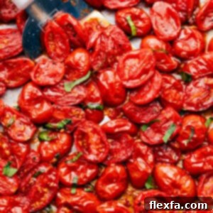 A close-up shot of roasted cherry tomatoes in a bowl, garnished with fresh basil.
