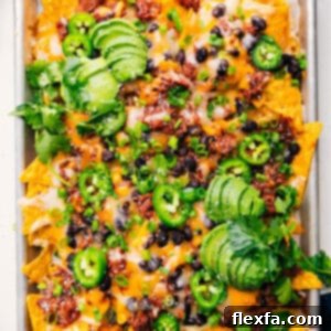 A close-up shot of a platter of freshly baked Pulled Pork Nachos, with emphasis on the crispy chips, melted cheese, and savory pulled pork.