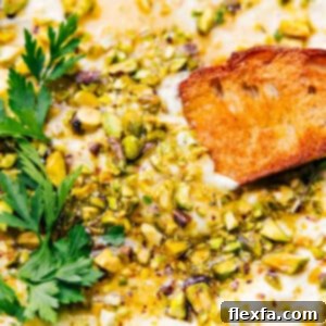 Close-up of creamy whipped feta dip topped with golden honey and crunchy pistachios, ready for serving.