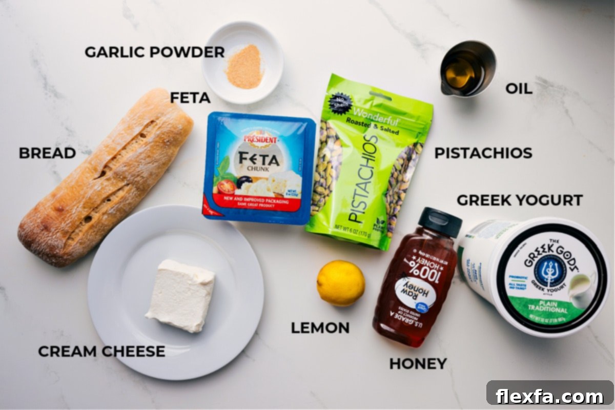 Ingredients In Whipped Feta Recipe All the essential ingredients for making whipped feta: a block of feta, cream cheese, Greek yogurt, lemon, olive oil, and garlic powder. Toppings include honey, pistachios, and fresh crostini for serving.