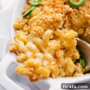 A vibrant close-up of Jalapeño Popper Mac and Cheese in a baking dish, showcasing its gooey cheese, crispy bacon, and golden topping.
