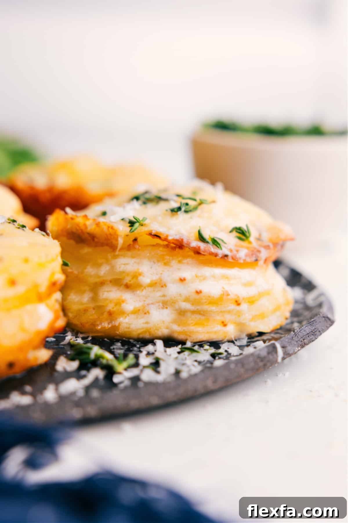 Potato stacks recipe fresh from the oven topped with melted cheese and thyme. Golden brown and bubbly with herbs.